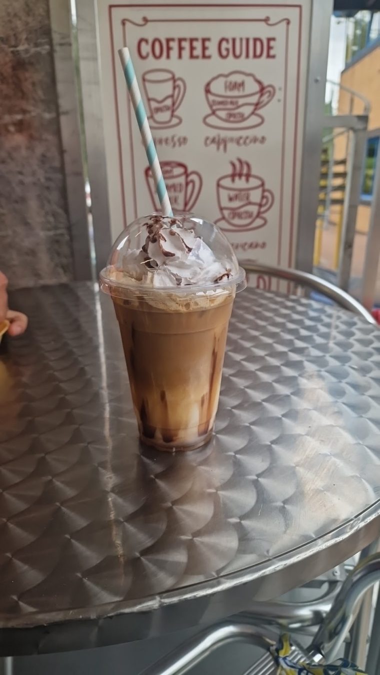 An iced coffee with whipped cream and syrup in a clear cup
